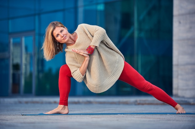 Hermosa joven practica yoga asana Parivritta Parshvakonasana