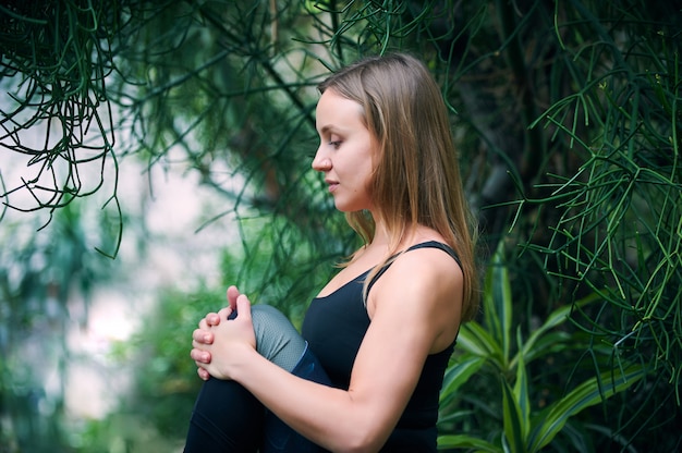 Hermosa joven practica yoga asana en la selva.