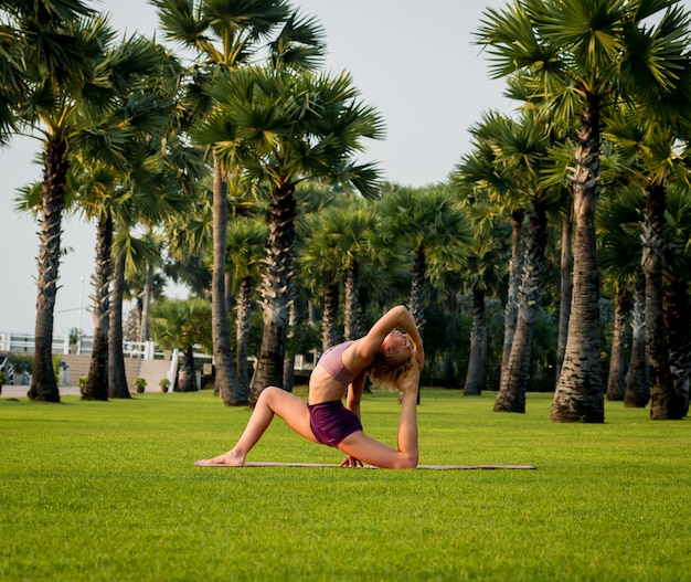 Hermosa joven practica yoga en la playa. Ejercicio temprano en la mañana