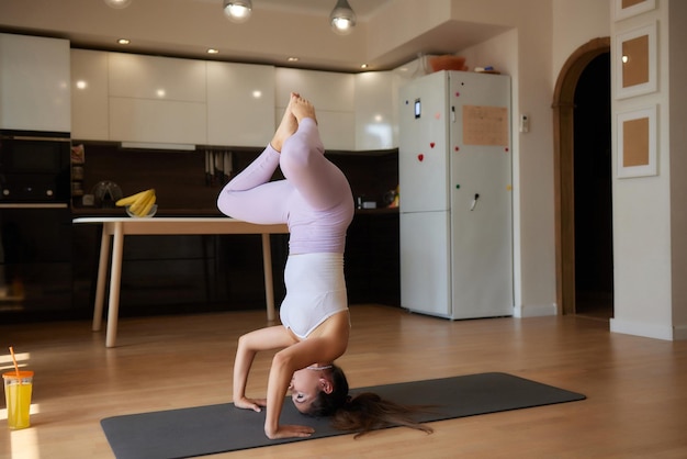 Hermosa joven practicando yoga en casa