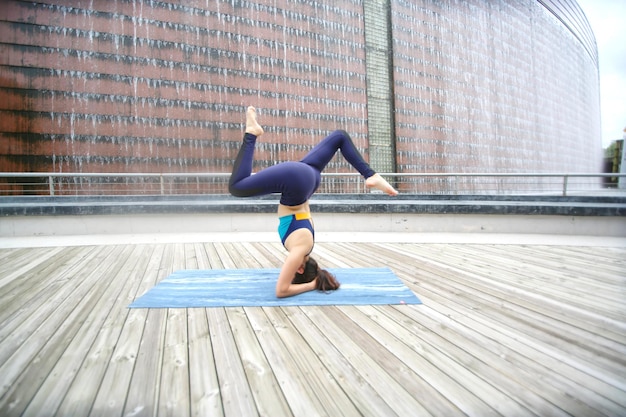 Hermosa joven practicando yoga en la terraza de madera