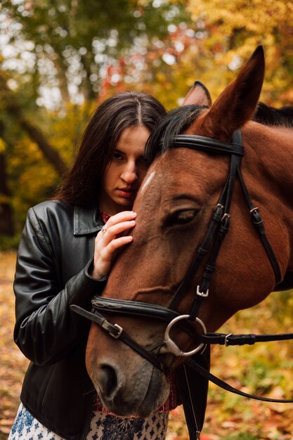 Hermosa joven presiona su cabeza contra un caballo marrón