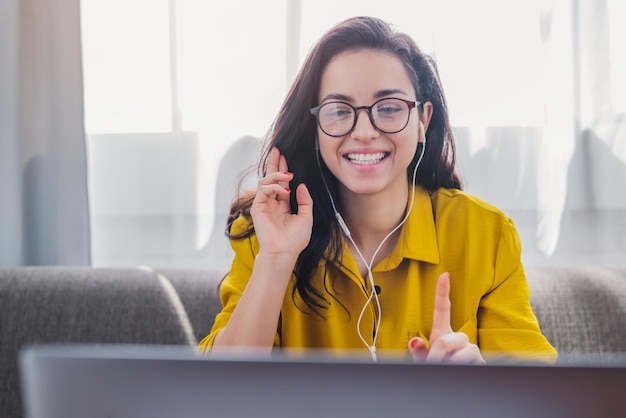 Hermosa joven que usa una videollamada en una laptop para conectarse con amigos