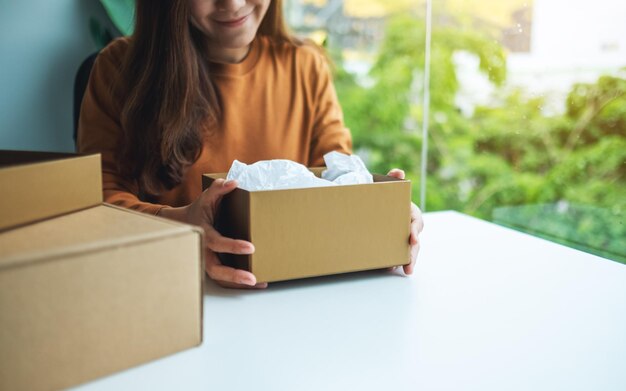 Una hermosa joven recibiendo y abriendo un paquete postal de ropa en casa para la entrega y el concepto de compra en línea