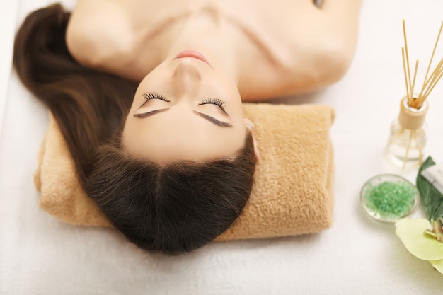 Hermosa joven recibiendo masaje facial acostado en el sofá