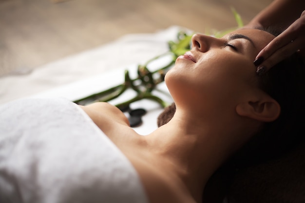 Hermosa joven recibiendo un tratamiento facial en el salón de belleza.