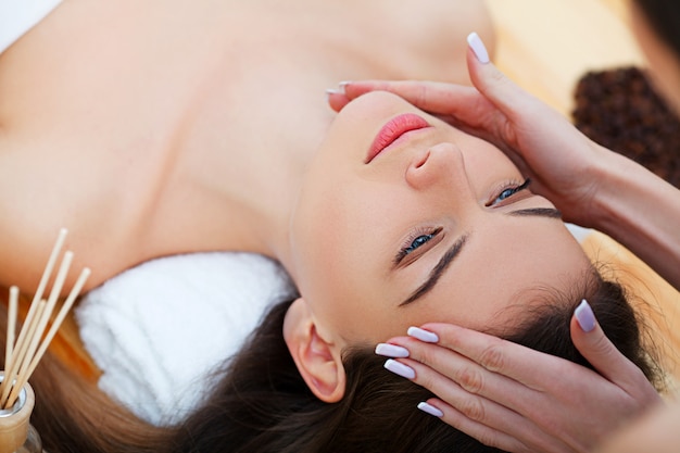 Hermosa joven recibiendo un tratamiento facial en el salón de belleza.