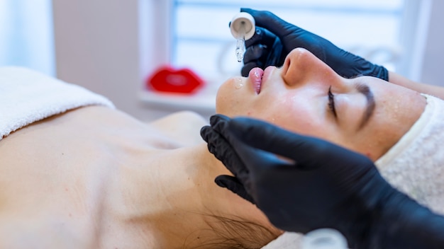 Hermosa joven recibiendo un tratamiento facial en el salón de belleza.