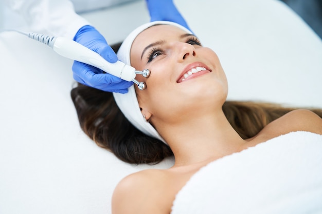 Hermosa joven recibiendo un tratamiento facial en el salón de belleza.