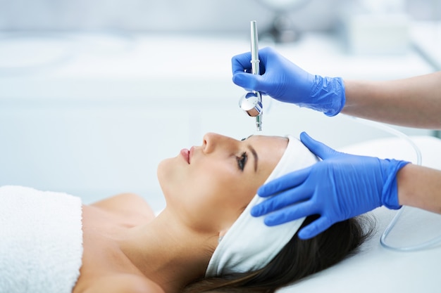 Hermosa joven recibiendo un tratamiento facial en el salón de belleza.