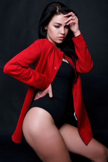 Hermosa joven regordeta en cuerpo negro de pie sobre un fondo negro. Plus size modelo de moda sexy en lencería, mujer gorda sobre fondo negro de estudio, cuerpo de la mujer con sobrepeso, retrato de cuerpo entero