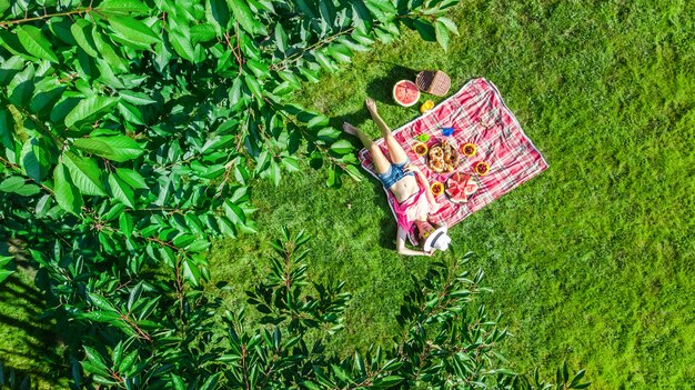 Hermosa joven relajándose en el césped, con picnic de verano en el parque al aire libre