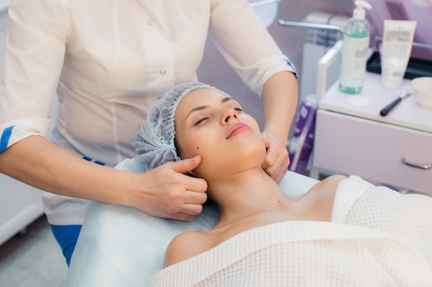 Hermosa joven relajante con masaje facial en el spa de belleza