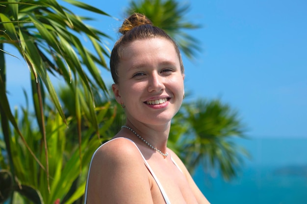 Hermosa joven relajarse en un traje de baño en el techo cerca de la piscina tomando el sol en el mar de verano y las islas de fondo hotel de lujo