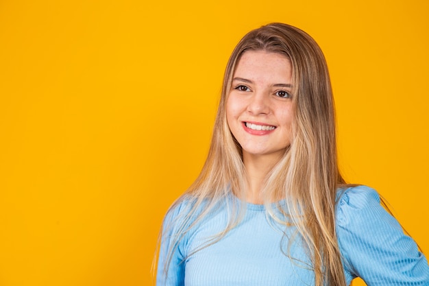 Hermosa joven rubia caucásica felizmente. Concepto de éxito y logro. Alegre mujer bonita rubia sobre fondo amarillo.