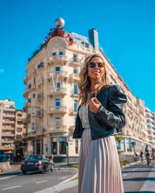 Hermosa joven rubia caucásica en un vestido de noche y una chaqueta de cuero negro