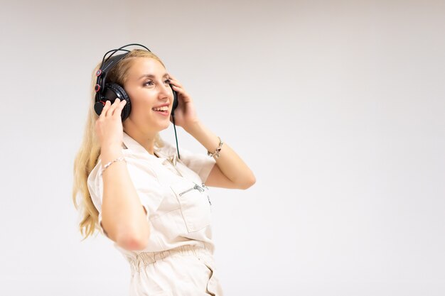 Hermosa joven rubia escuchando música sobre fondo blanco.