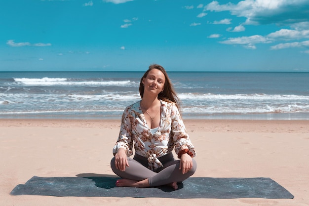 Hermosa joven rubia haciendo yoga pilato en la playa