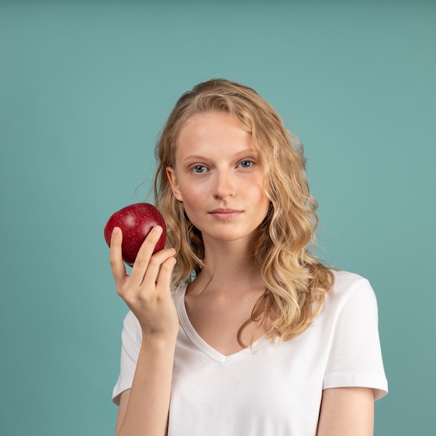 Hermosa joven rubia inteligente seria sin maquillaje con manzana roja