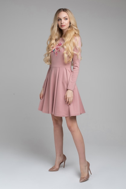 Hermosa joven rubia modelo en vestido rosa.