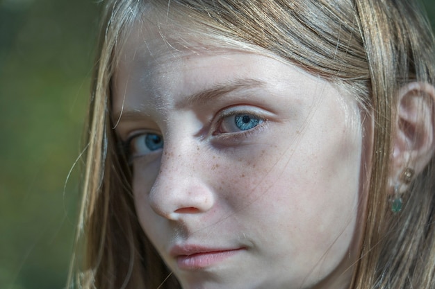 Hermosa joven rubia con pecas al aire libre sobre fondo de naturaleza en otoño, retrato de cerca