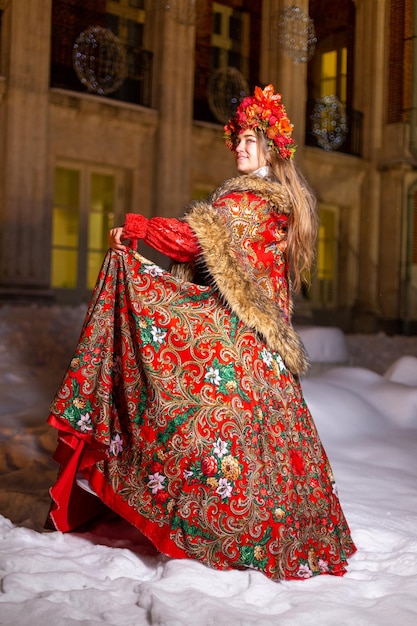 Hermosa joven rubia de pelo largo en ropa nacional tradicional rusa en invierno