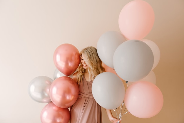 Hermosa joven rubia sonriente con globos blancos grises y rosados