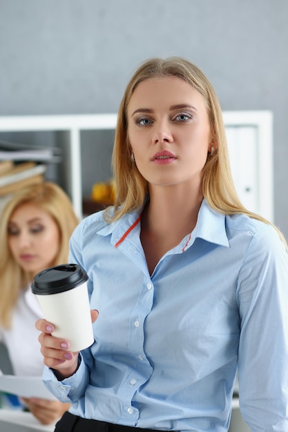 Hermosa joven rubia sosteniendo una taza caliente de bebida de café pausa del trabajo