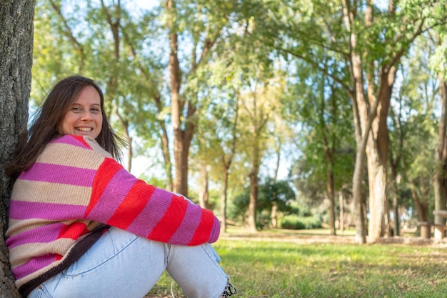 Hermosa joven sentada en un árbol en el parque