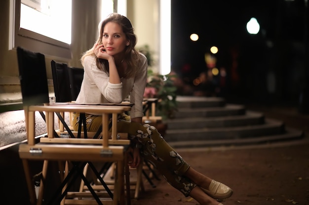 Hermosa joven sentada en un café de la calle por la noche