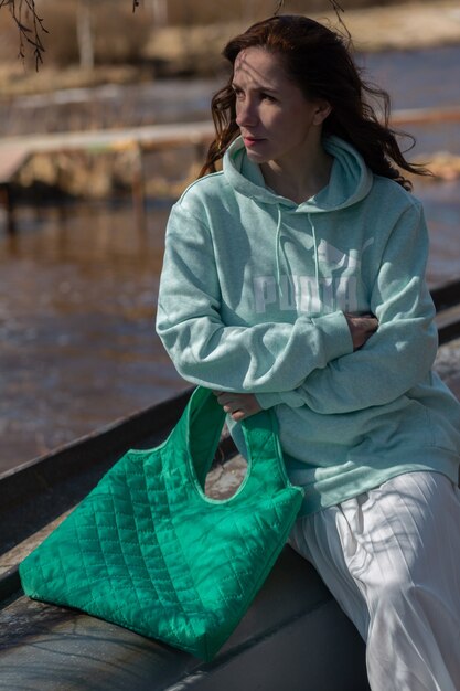 hermosa joven sentada junto al lago y disfrutando del sol