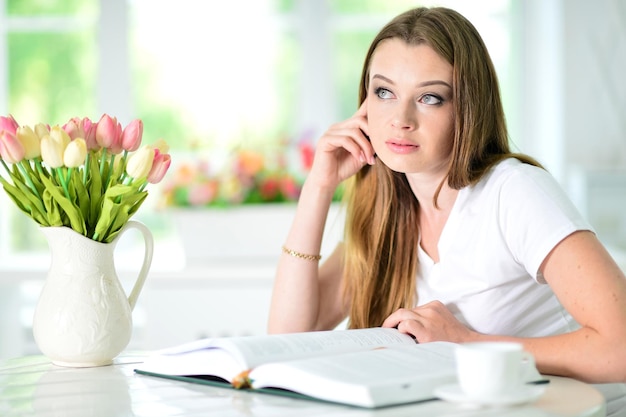 Hermosa joven sentada con libro abierto