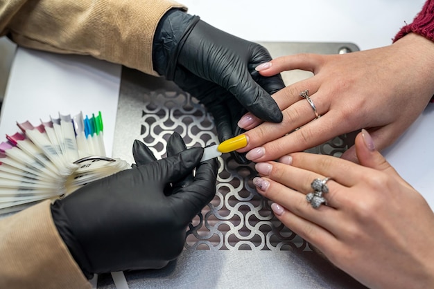 Hermosa joven sentada en una manicura en un prestigioso salón de un buen maestro de manicura. Concepto de manicura durante la epidemia.