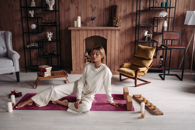 Hermosa joven sentada relajándose en la estera con velas en el interior de casa elegante y acogedor confort con muebles cómodos. Foto de alta calidad