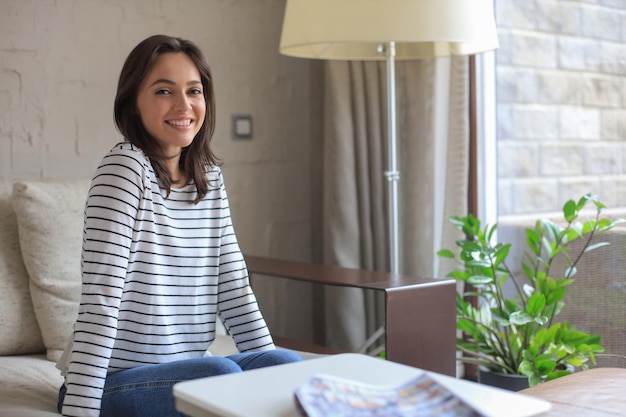 Foto hermosa joven sentada en un sofá en el interior