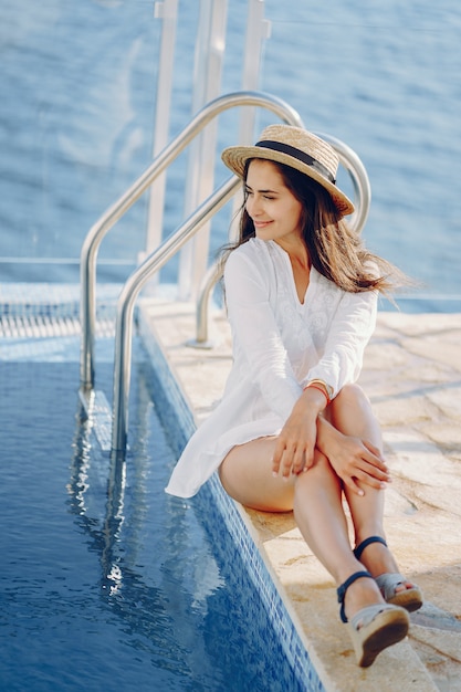 Una hermosa joven sentada en una terraza de verano y mirando el océano