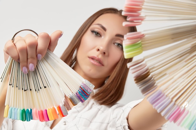 Hermosa joven seria mirando a la cámara sosteniendo puntas de uñas retrato de belleza de chica morena