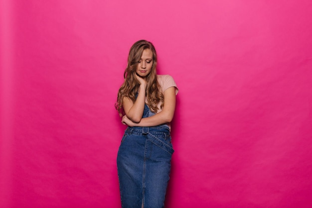 Foto hermosa joven seria está pensando y pensativa sobre un fondo rosa aislado. la chica carismática muestra el concepto de emociones en un estudio profesional.