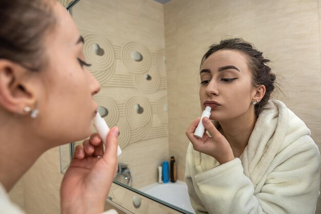 Hermosa joven sexy corrige su maquillaje que fue borrado en una bata de baño Concepto de maquillaje