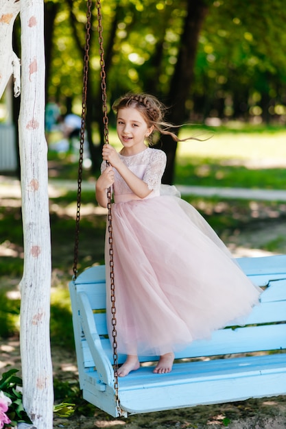 Una hermosa joven se sienta en el parque en un banco.