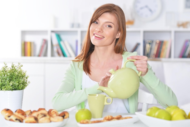 Hermosa joven sirviendo té en una taza