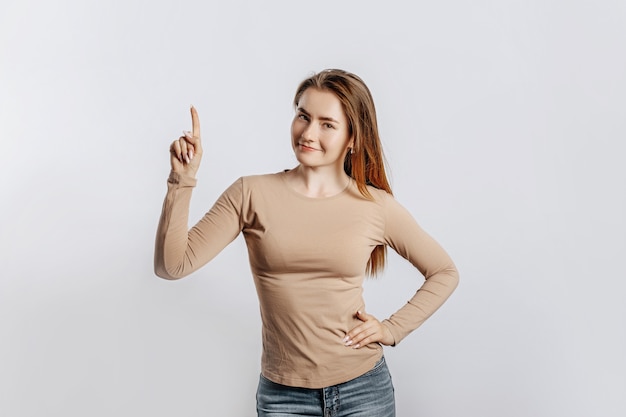 Hermosa joven sonriendo y apuntando hacia el lado sobre un blanco aislado