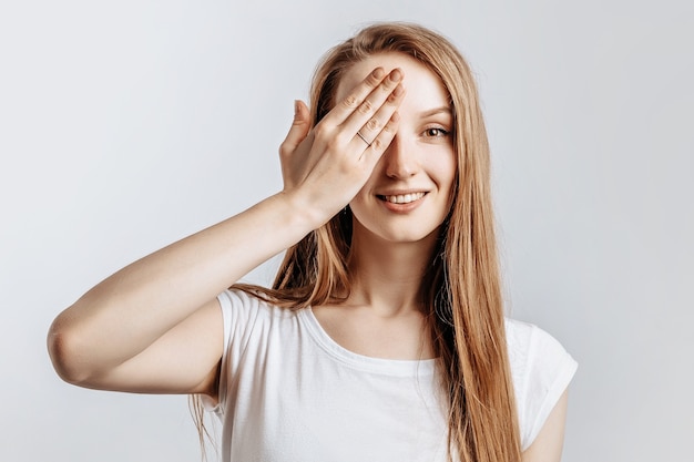 Foto hermosa joven sonriendo y cubriendo la mitad de su rostro con la mano