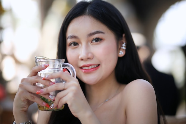 Hermosa joven sonriendo mientras sostiene un vaso de agua en casa