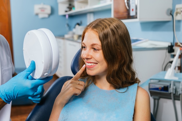 Hermosa joven sonriendo en su visita al dentista.