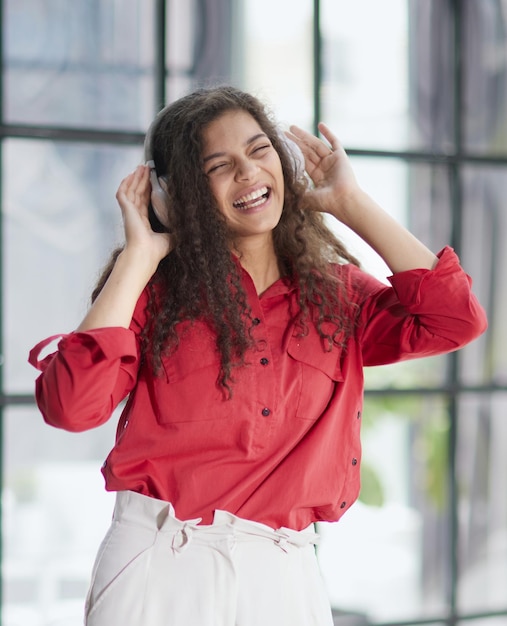 Hermosa joven sonriente con auriculares en la oficina moderna