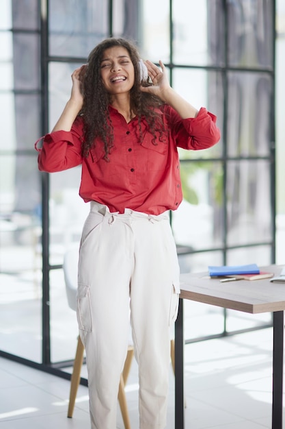 Hermosa joven sonriente con auriculares en la oficina moderna