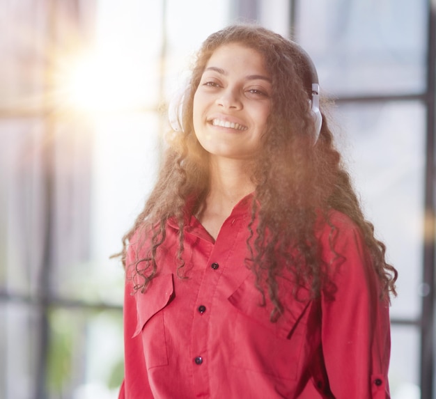 Hermosa joven sonriente con auriculares en la oficina moderna