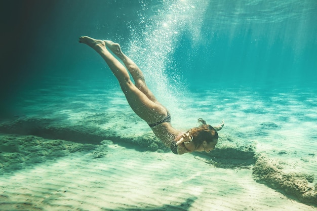 Hermosa joven sonriente nadando bajo el agua en el mar.