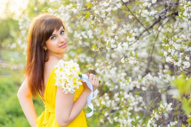 Hermosa joven sonriente con un ramo de flores al aire libre en primavera